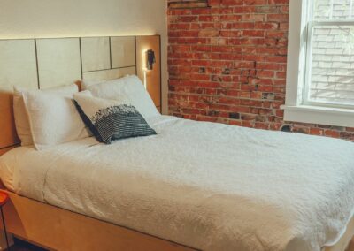 Queen bed next to exposed brick wall