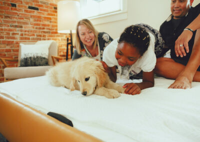 A couple a child and a puppy on a pull-out bed
